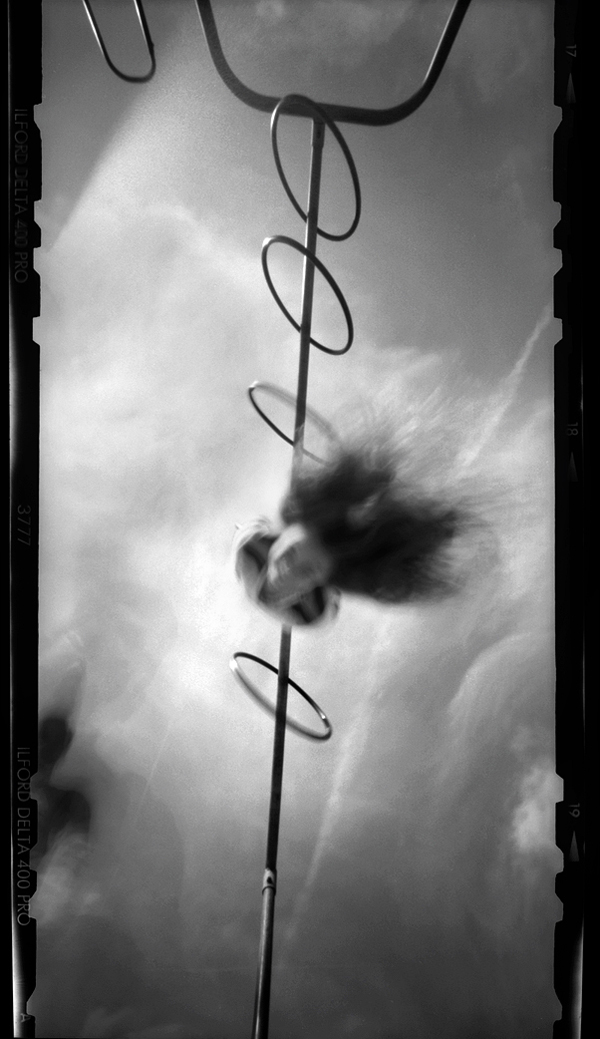 Black and white 6x12 ZeroImage pinhole photograph of a young girls handing from the monkey bars at a playground