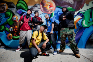 Group photo of five hip-hop dancers in front of colorful graffiti art mural in Chicano Park in San Diego, California