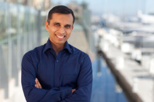 Business man wearing blue button down shirt smiling and standing next to a dock