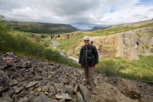 Chris Keeney standing on the Glymur waterfall trail with the Botnsá river and Hvalfjordur Fjord in the background.