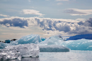 A view of ice and Icebergs floating in water in the Jökulsárlón Glacier Lagoon in Iceland. Blue sky with puffy clouds all blend together in dance of shape and color