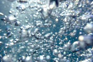 Air bubble rising to the surface of the blue water and sparkling in the sunlight in ocean off the coast of La Jolla beach in San Diego