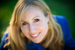 landscape oriented headshot of a blonde woman with blue eyes and jacket smiling at the camera in San Diego California