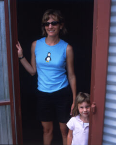 a woman and a small child standing in a doorway of a metal barn together smiling at the camera