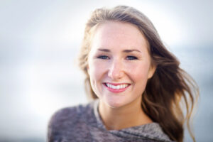 Head and shoulders color photograph of a teenage girl with blonde hair smiling at the camera