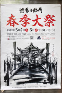 photograph of a poster in downtown Tokyo about Toyokawa Inari Spring Festival. The black and white brushstrokes is done in a passionate style with thick and thins with splatter textures