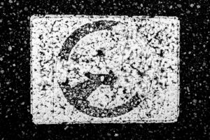 black and white abstract photograph of a street marking with white blob like shapes and a circle in the middle.