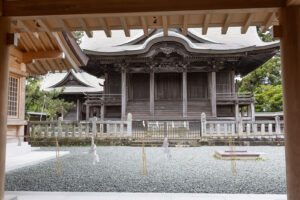 Looking into the inner courtyard (which is roped off) at the historic Japanese architecture of the Aso Jinja Shrine in Japan. Beautiful woodwork with a mixture of curved and straight lines make for a impressive looking building.