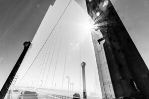 Black and white abstract double exposure photograph of cars and bicyclists traveling across the Golden Gate Bridge in San Francisco, California