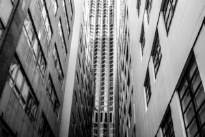 Black and white monochrome street photograph of three skyscrapers visually blended together.