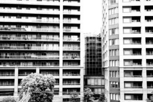 Black and white photograph of apartment building structures with window, balconies, wires and urban landscaping in Tokyo, Japan